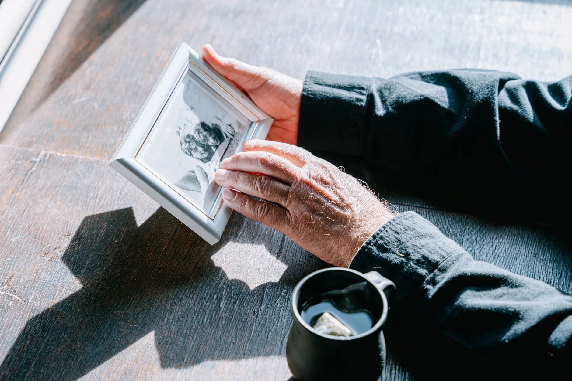 Hands holding a framed photo of a dog, reflecting on anticipatory grief before pet loss