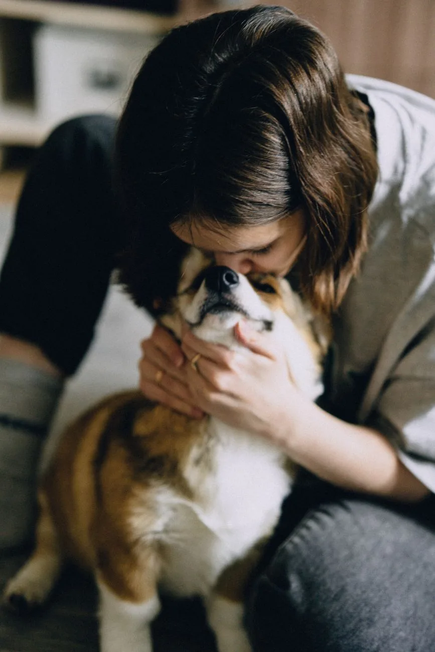 Woman tenderly kissing and cradling her dog, showing the deep bond and emotions of pet loss grief.