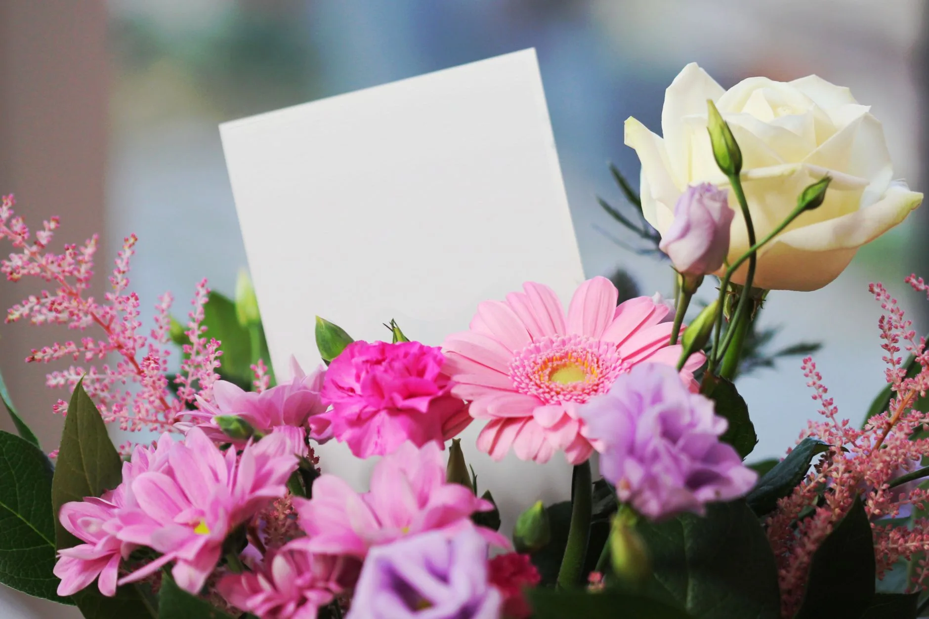 Blank sympathy card tucked into pink and white floral bouquet for pet memorials and condolence messages